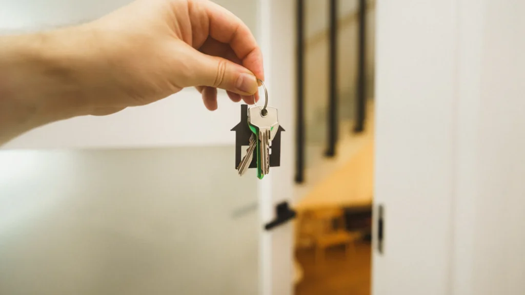 Mão segurando a chave na porta de um imóvel novo